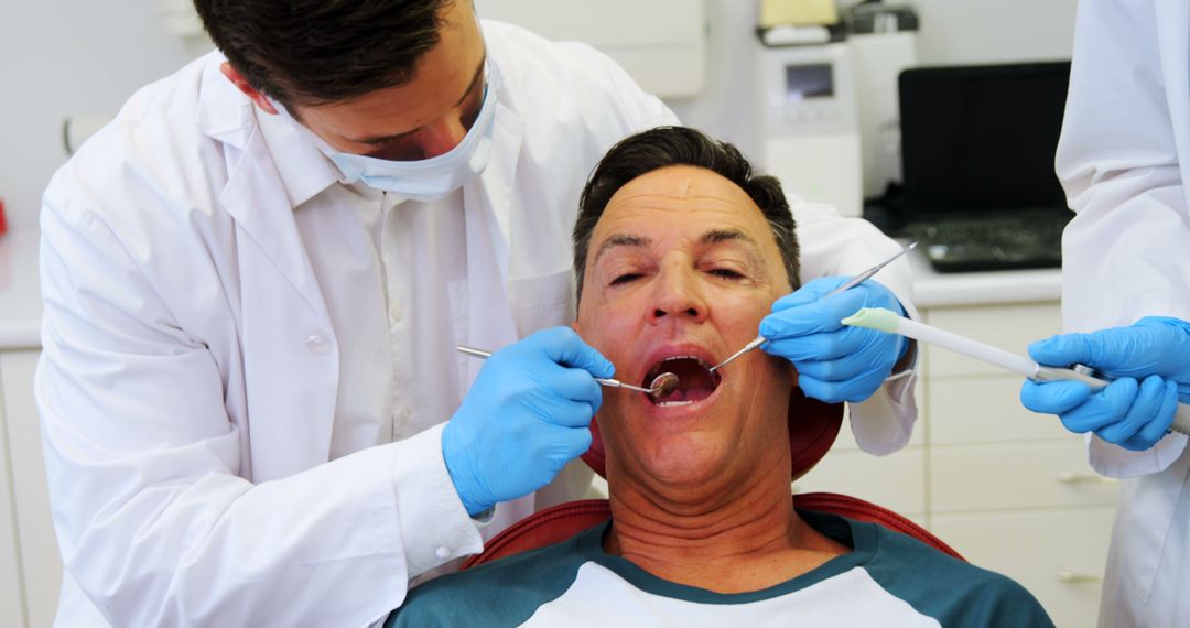 Dentist Examining Mature Male Patient in Dental Office - Free Images, Stock Photos and Pictures on Pikwizard.com