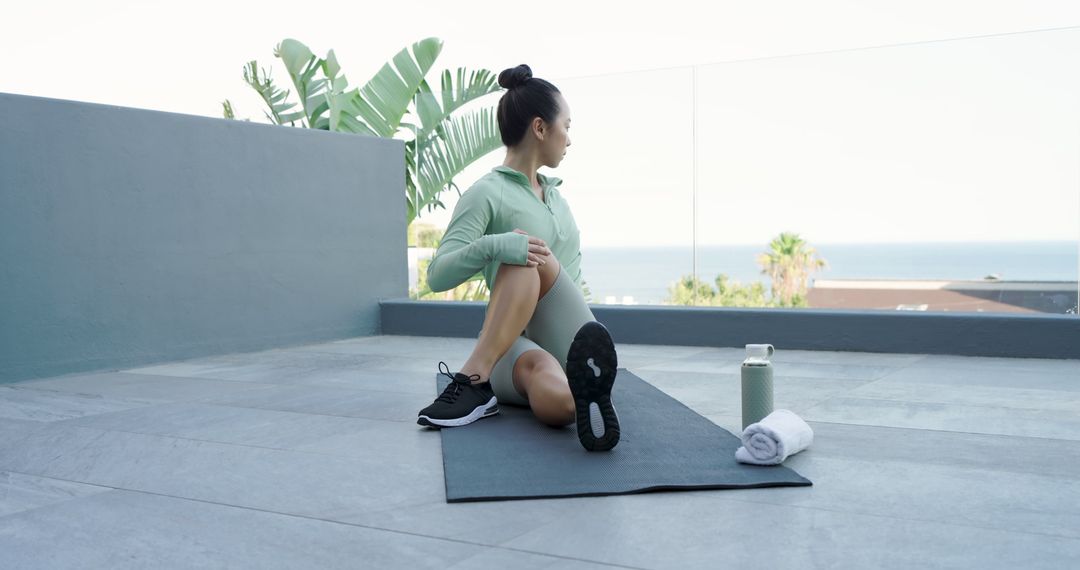 Woman Practicing Yoga Twists on Rooftop With Scenic Ocean View