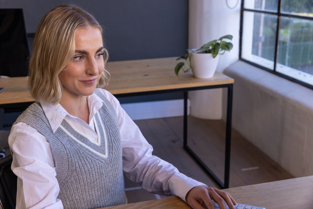 Blonde Professional Typing on Keyboard at Modern Office Desk