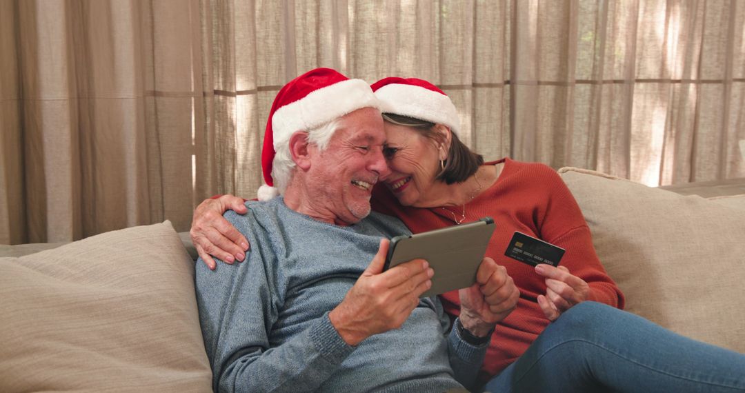 Senior Couple in Santa Hats Using Tablet and Credit Card at Home