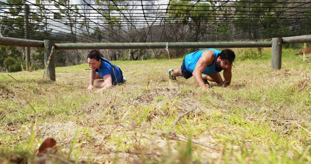 Two Adults Crawling Under Netted Obstacle in Outdoor Adventure Race - Free Images, Stock Photos and Pictures on Pikwizard.com