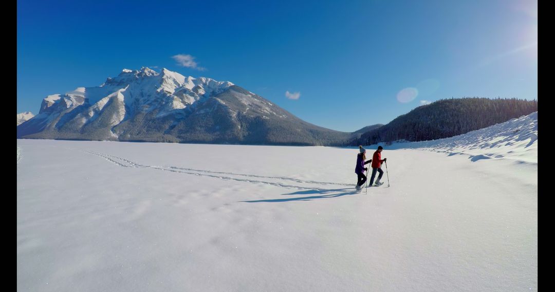 Couple Snowshoeing on Vast Snow-Covered Landscape with Majestic Mountain Backdrop - Free Images, Stock Photos and Pictures on Pikwizard.com