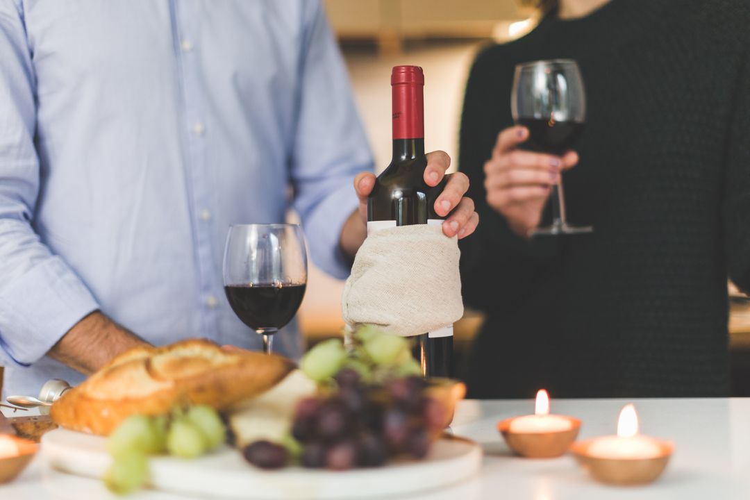 Couple Enjoying Wine and Grapes at Candlelit Table