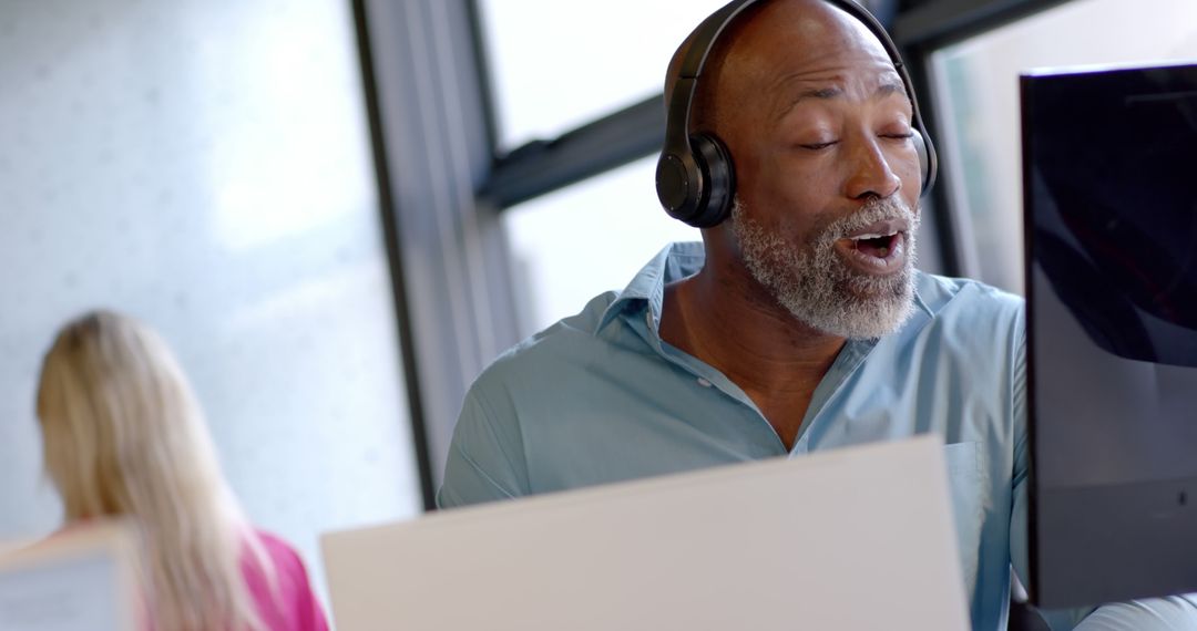 Happy African American Man Wearing Headphones at Office Desk - Free Images, Stock Photos and Pictures on Pikwizard.com