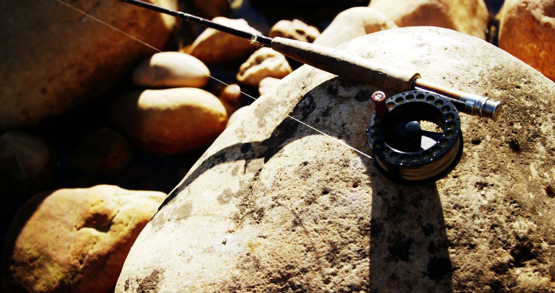Fishing Rod and Reel Resting on Sunlit Rocks - Free Images, Stock Photos and Pictures on Pikwizard.com