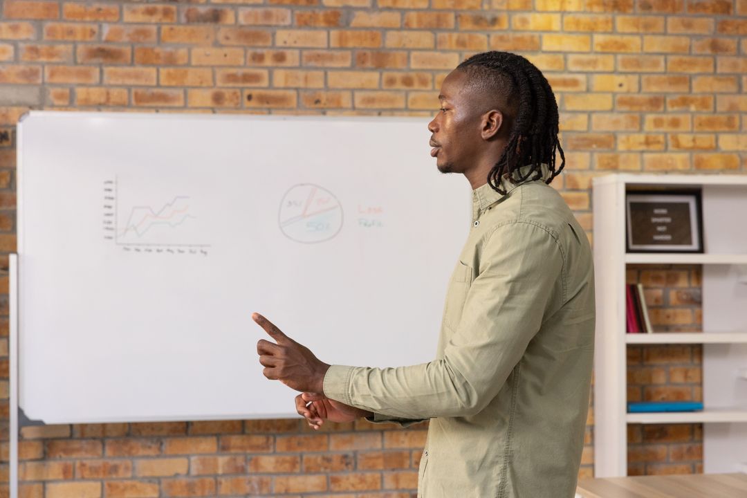 African American Man Presenting Data on Office Whiteboard
