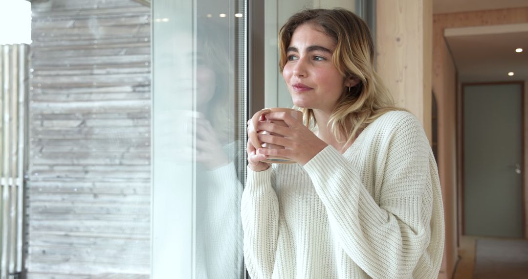 Thoughtful Woman Enjoying Warm Drink by Window in Modern Home Setting