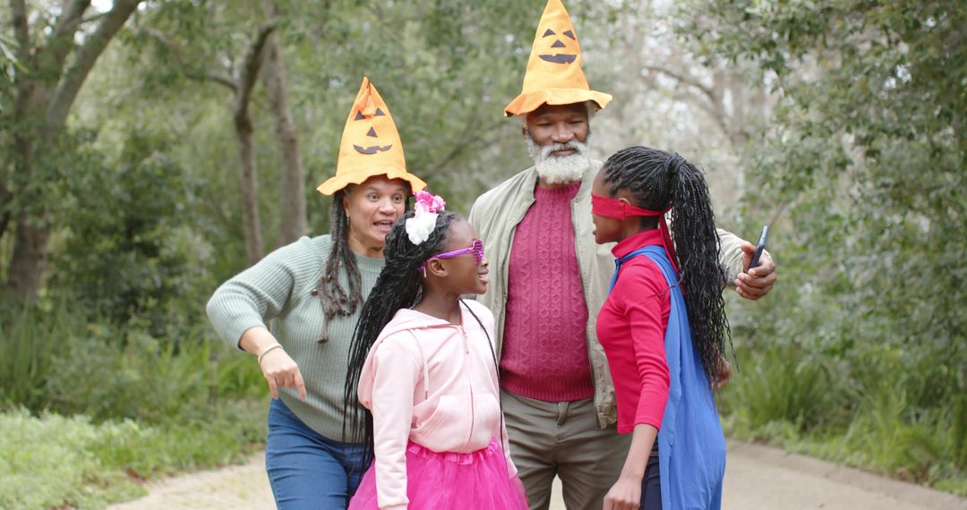 Happy Multigenerational Family Wearing Pumpkin Hats Playing Blindfold Game in Park
