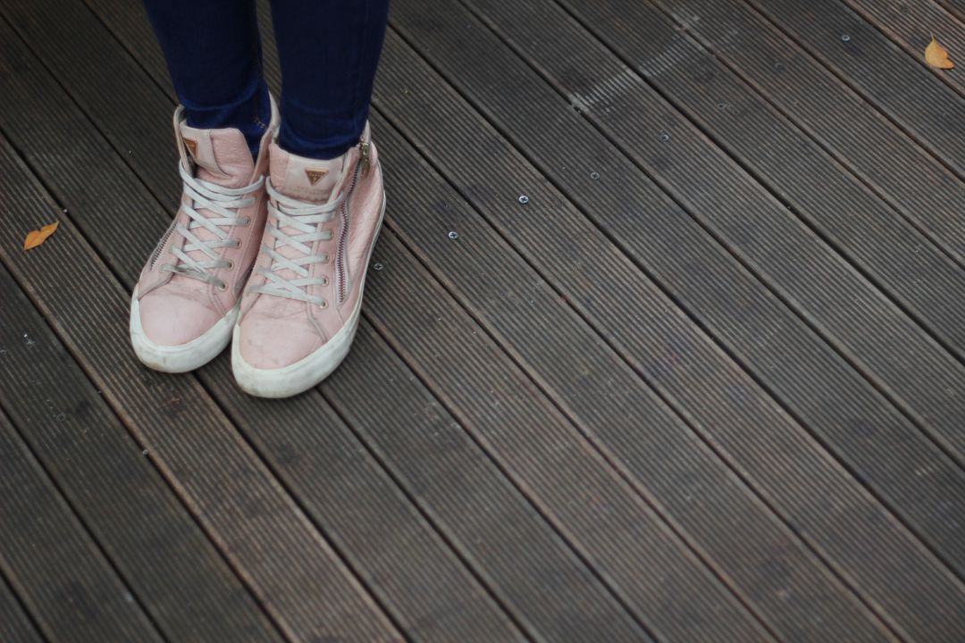 Person Wearing Pink Sneakers and Blue Jeans on Wooden Deck - Free Images, Stock Photos and Pictures on Pikwizard.com