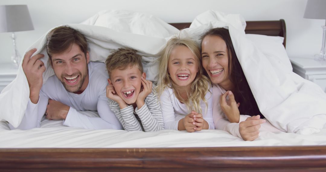 Happy Family Smiling and Cuddling Under Covers Together - Free Images, Stock Photos and Pictures on Pikwizard.com