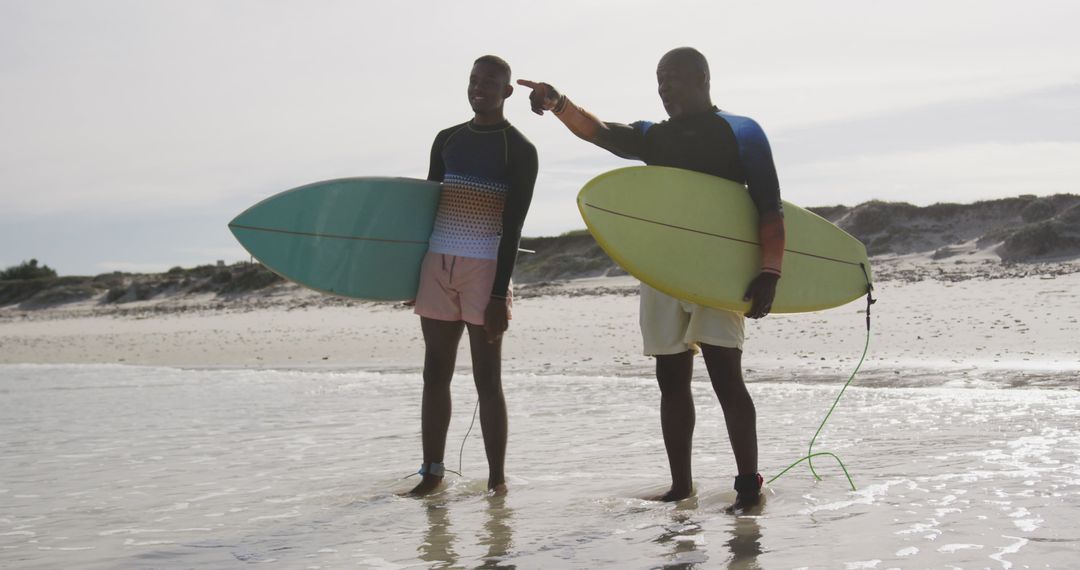 Two Black Surfing Friends Standing in Shallow Water Holding Surfboards - Free Images, Stock Photos and Pictures on Pikwizard.com