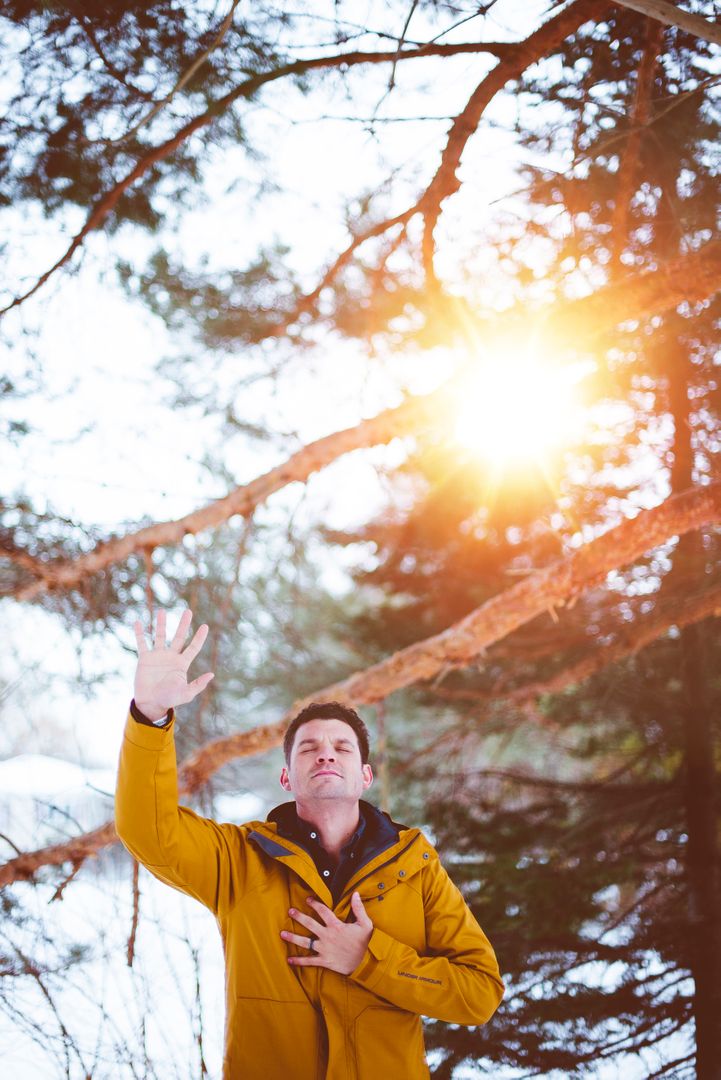 Man in Yellow Jacket Raising Hand at Sunset in Snowy Forest - Free Images, Stock Photos and Pictures on Pikwizard.com