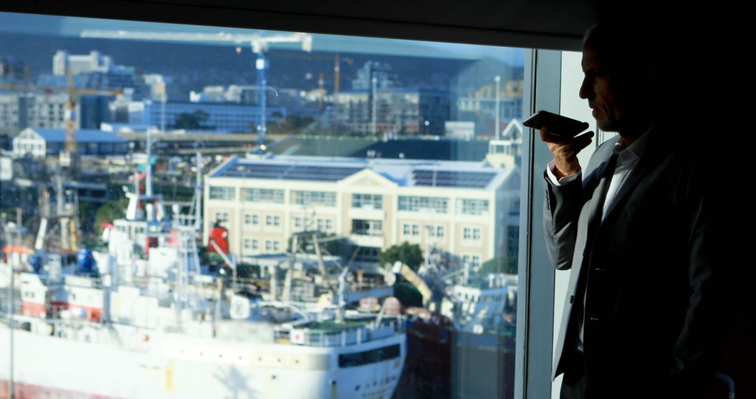 Businessman Making a Call at Office Window with Harbor View - Free Images, Stock Photos and Pictures on Pikwizard.com