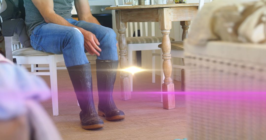 Man in Wellingtons Sitting Indoors with Bright Flare