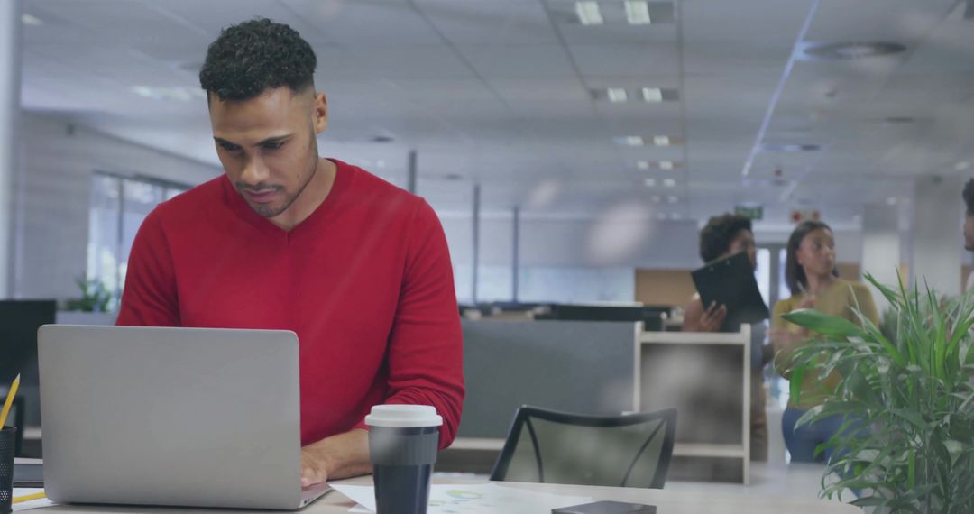 Focused Professional Man Typing at Laptop in Open-Plan Office