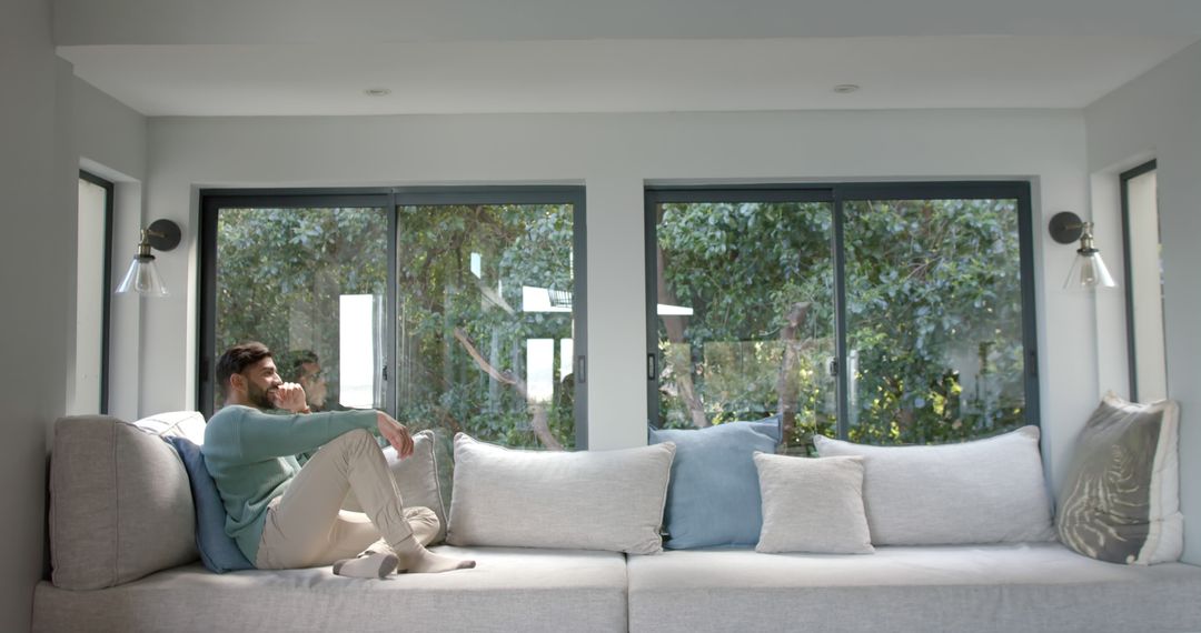 Man Relaxing on Cozy Sofa by Window at Home - Free Images, Stock Photos and Pictures on Pikwizard.com