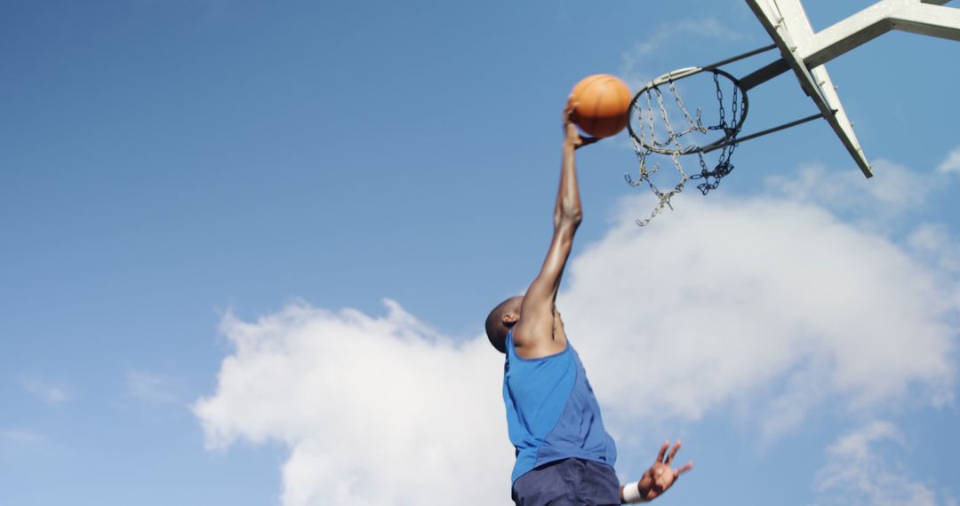 Athlete Dunking Basketball on Outdoor Court with Blue Sky - Free Images, Stock Photos and Pictures on Pikwizard.com