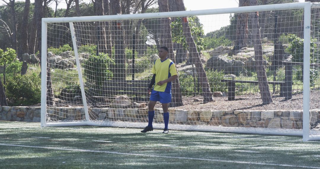 Soccer Player in Action Near Goalpost on Sunny Day