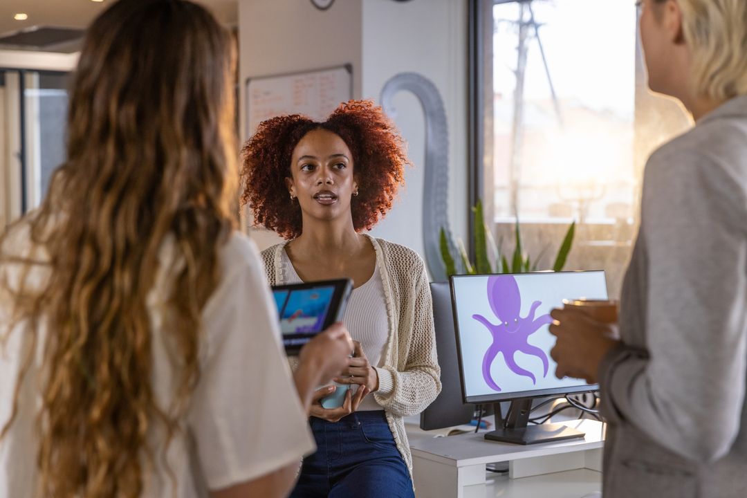 Diverse Women Collaborating Around Office Desk in Modern Workspace