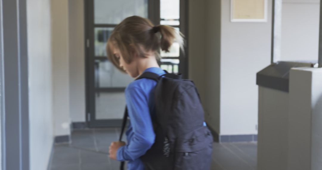 Young Student Walking School Corridor with Backpack