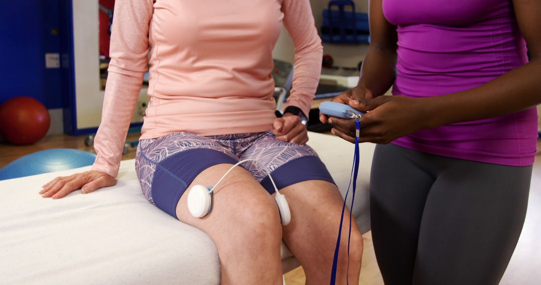 Physical therapist applying electrodes to senior woman's knees during rehabilitation - Free Images, Stock Photos and Pictures on Pikwizard.com