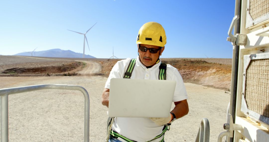 Engineer Working on Laptop at Wind Farm on Sunny Day - Free Images, Stock Photos and Pictures on Pikwizard.com