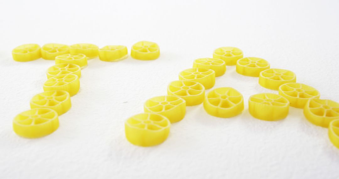 Alphabet Letters Formed with Yellow Pasta Wheels on White Background - Free Images, Stock Photos and Pictures on Pikwizard.com