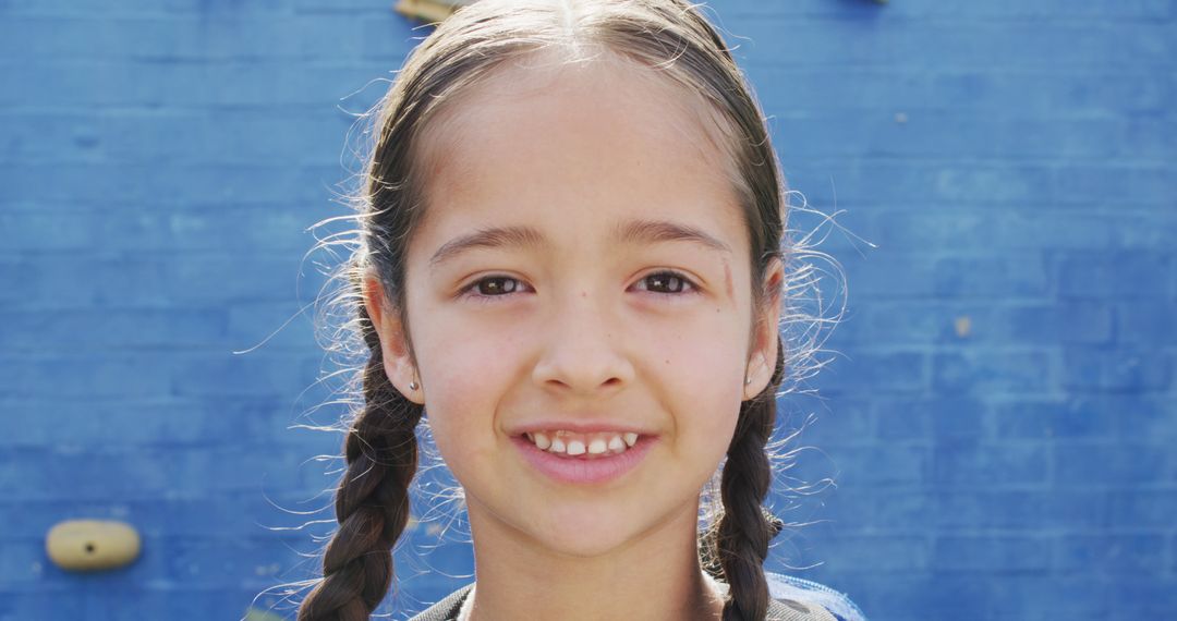 Smiling Girl with Braids in Front of Blue Wall - Free Images, Stock Photos and Pictures on Pikwizard.com