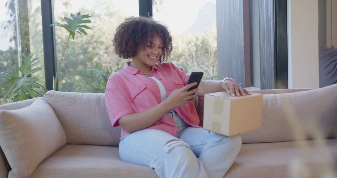 Happy Woman Checking Smartphone While Relaxing with Package on Sofa