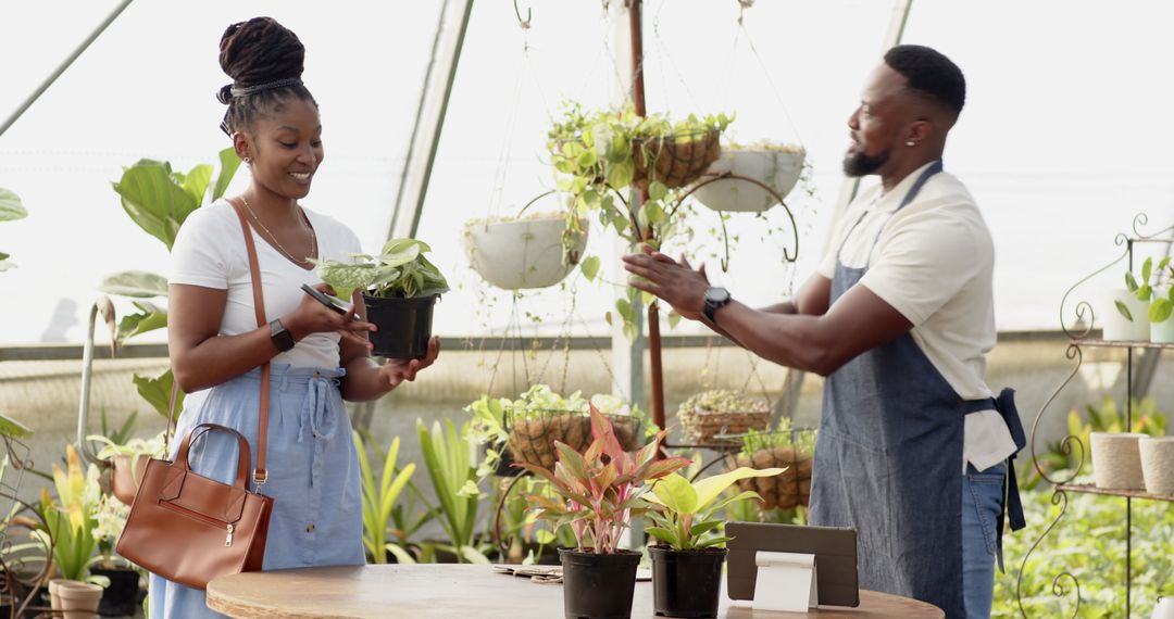 Smiling African American Couple Examining Plants in Greenhouse Nursery