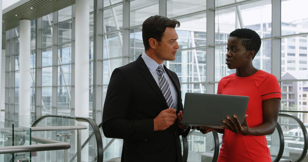 Caucasian businessman and African American professional woman discussing work using laptop in office - Free Images, Stock Photos and Pictures on Pikwizard.com