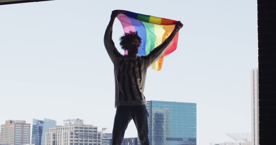 Person Holding LGBTQ+ Flag Against Urban Skyscrapers - Free Images, Stock Photos and Pictures on Pikwizard.com