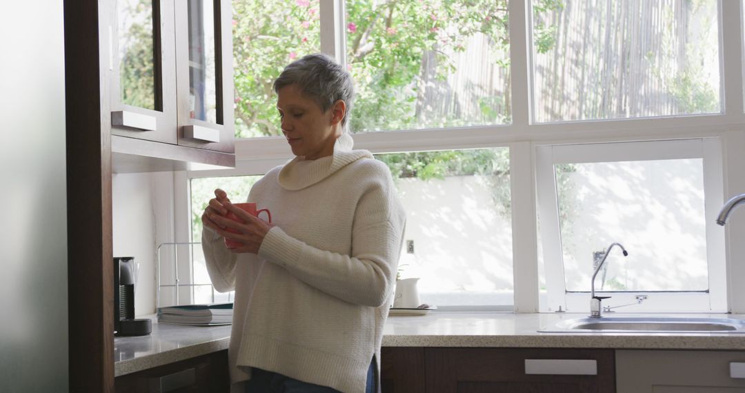 Woman Having a Hot Drink in a Bright Kitchen - Free Images, Stock Photos and Pictures on Pikwizard.com