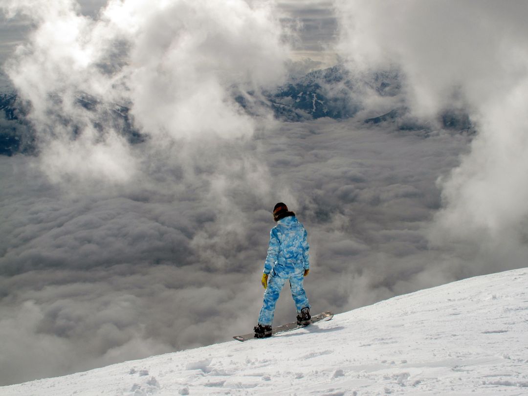 Snowboarder in Blue Suit Facing Cloudy Mountains - Free Images, Stock Photos and Pictures on Pikwizard.com