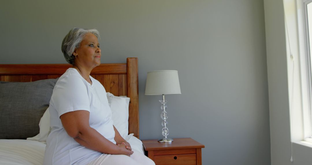 Senior Woman Sitting on Bed Peaceful Morning Contemplation - Free Images, Stock Photos and Pictures on Pikwizard.com