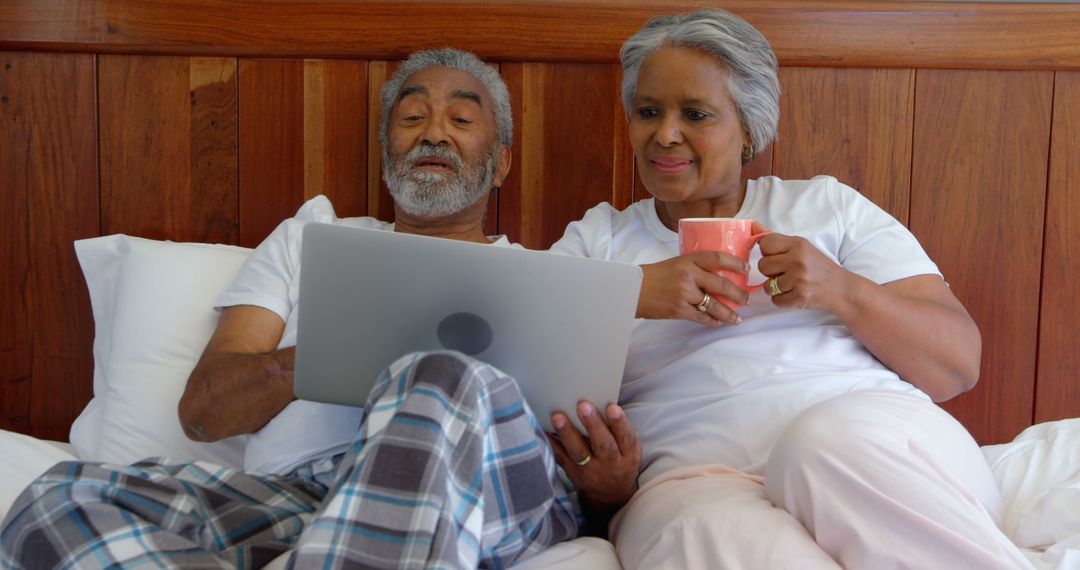 Senior Couple Enjoying Leisure Time with Digital Tablet in Bed
