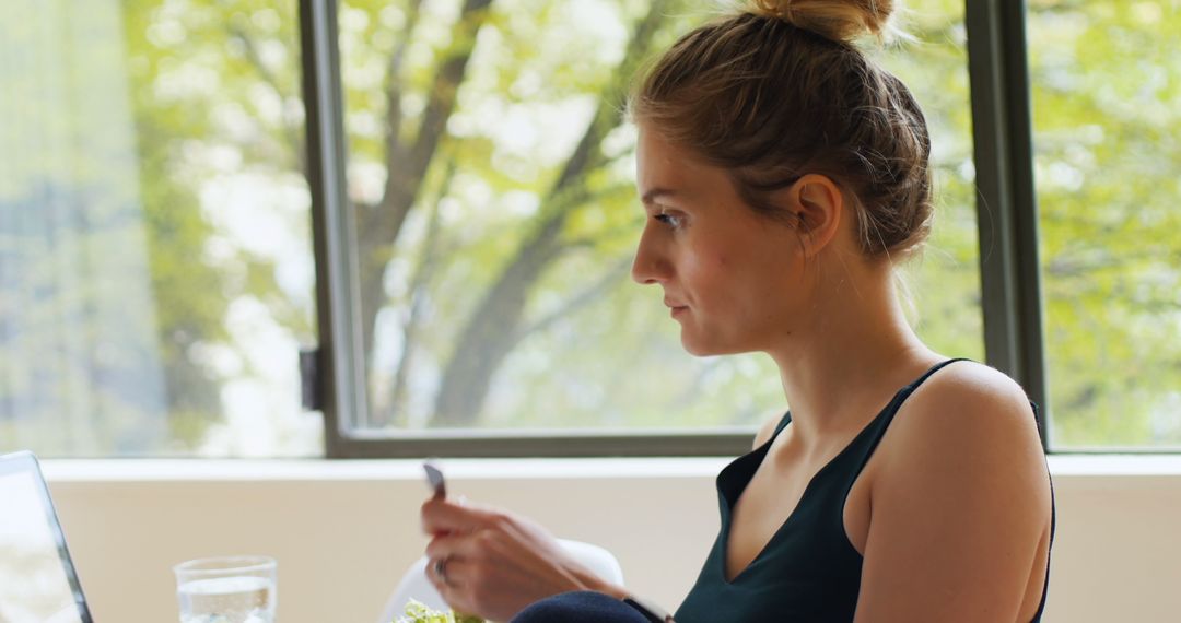 Woman Balancing Meal and Work on Laptop at Home