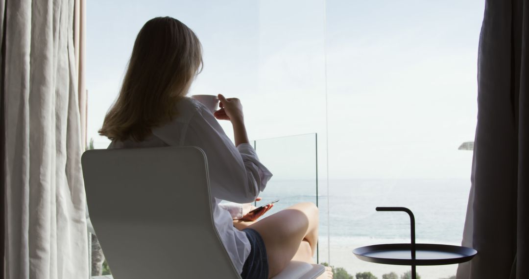 Woman Relaxing with Coffee by Beachside Window View - Free Images, Stock Photos and Pictures on Pikwizard.com