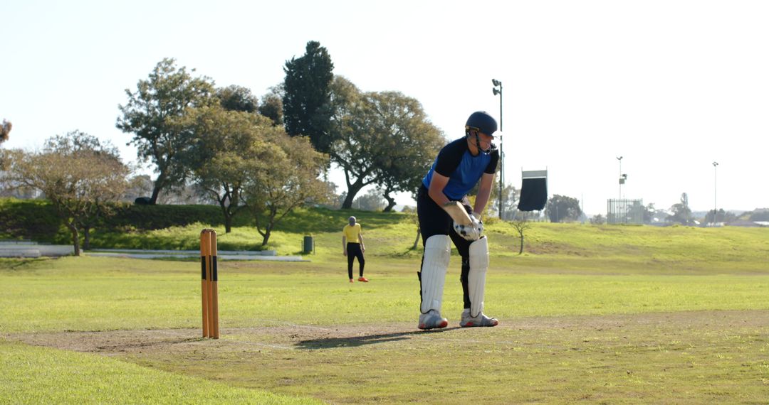 Male Cricketer in Action on Sunny Day at Outdoor Field