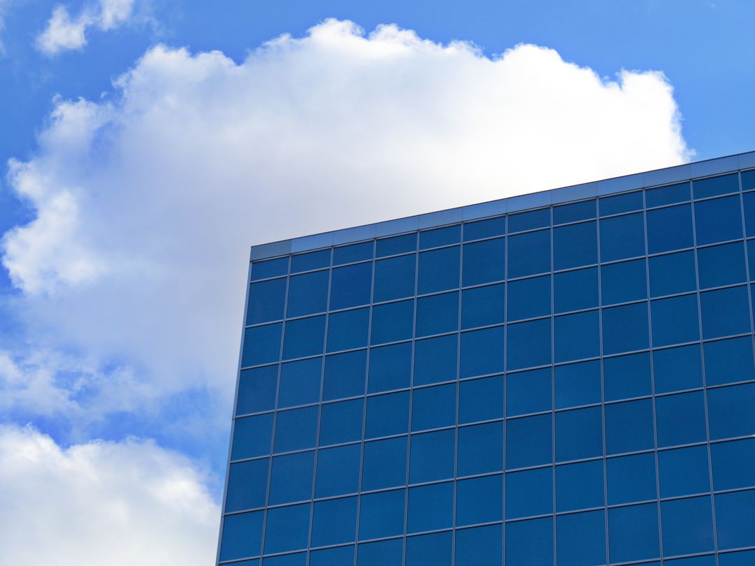 Modern Building with Reflective Windows Under Soft Cloudy Sky