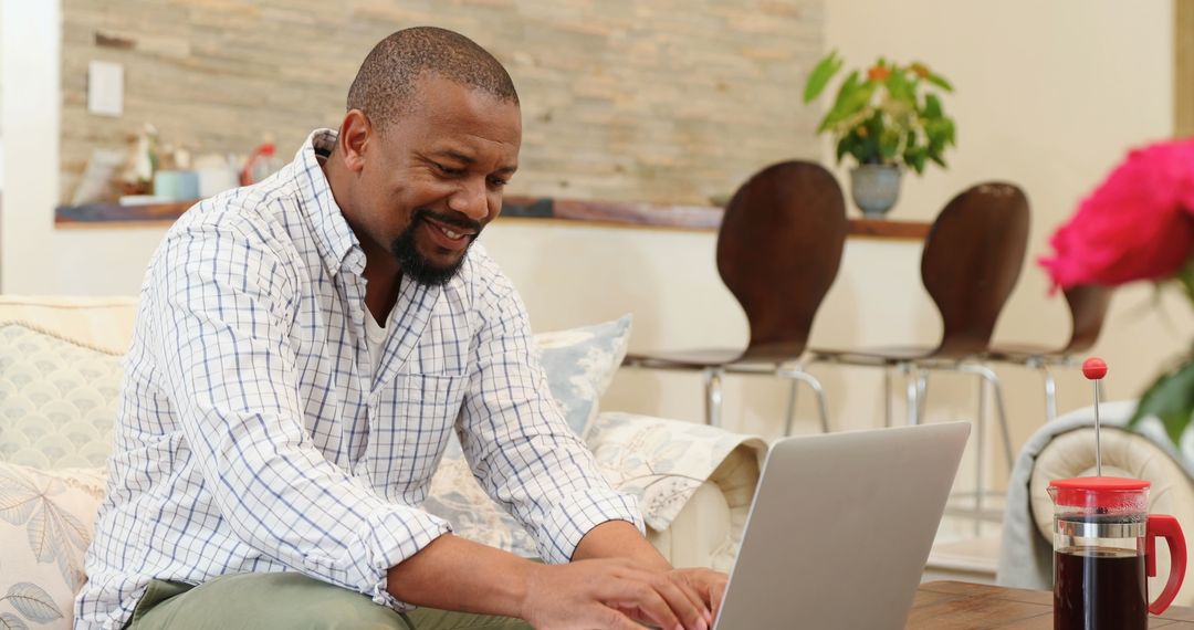 Man Engaging in Remote Work with Laptop and Coffee at Home