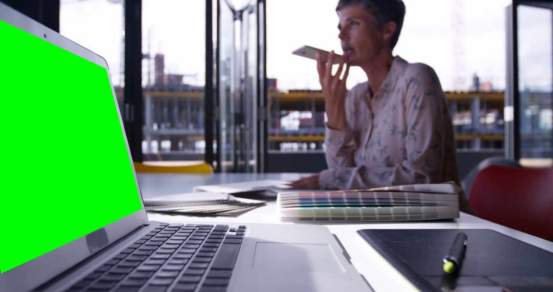 Businesswoman dictating a voice message near laptop with green screen in modern office - Free Images, Stock Photos and Pictures on Pikwizard.com