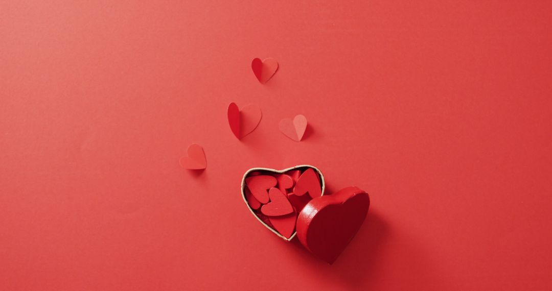 Heart-Shaped Box Filled with Red Paper Hearts on Red Background