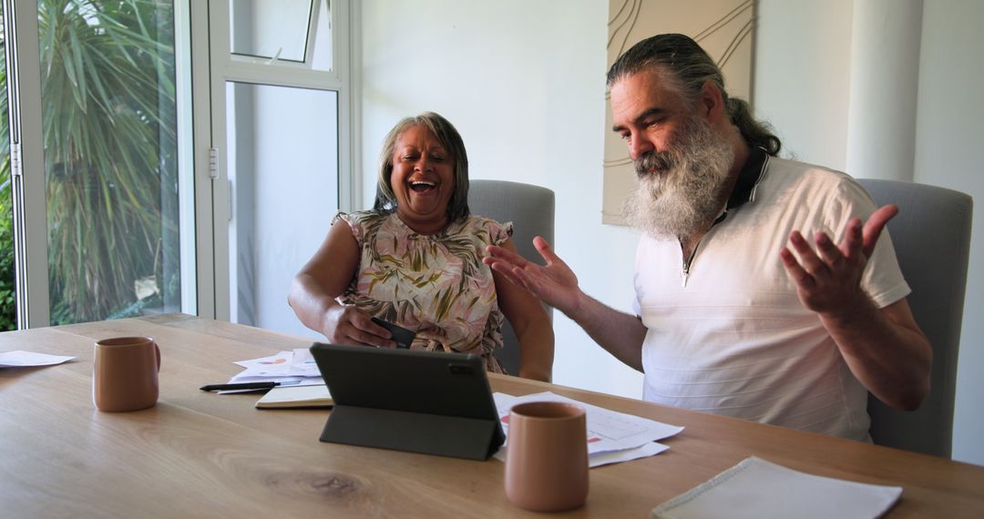 Senior Couple Discussing on Tablet Over Coffee at Home