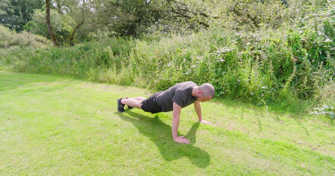 Man Exercising with Push-Ups on Grass in Sunny Park