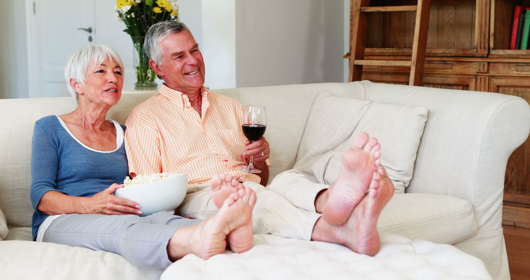 Senior Couple Relaxing on Couch with Wine and Popcorn - Free Images, Stock Photos and Pictures on Pikwizard.com