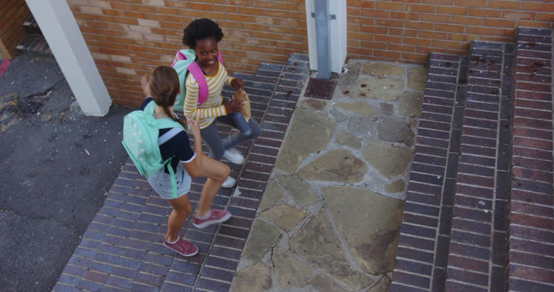 Two Diverse Girls Climbing School Steps with Backpacks