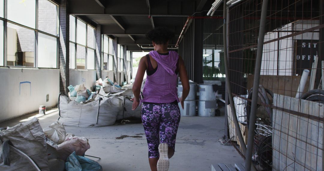 African american woman wearing sports clothing jogging through an empty urban building - Free Images, Stock Photos and Pictures on Pikwizard.com