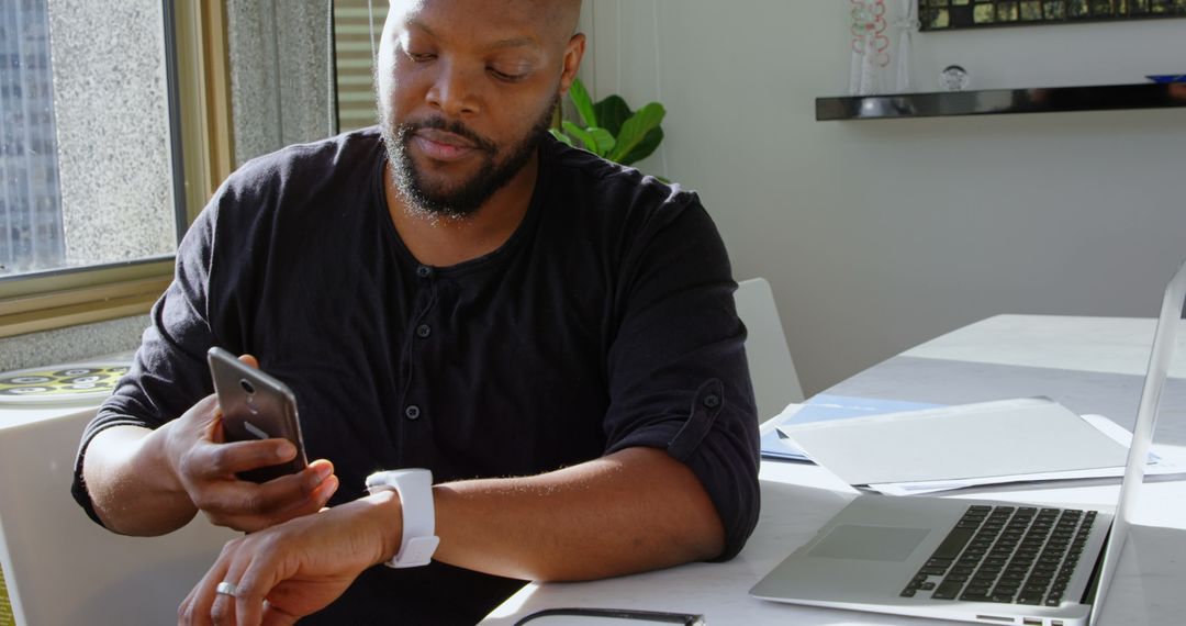 Man Using Smartwatch and Smartphone in Modern Home Environment