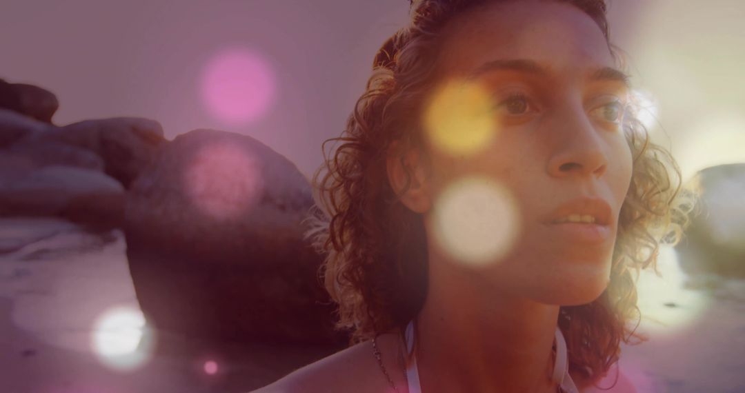 Woman by Beach Exuding Resilience and Serenity Amidst Bokeh Flares